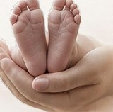 A newborn’s feet resting in open hands